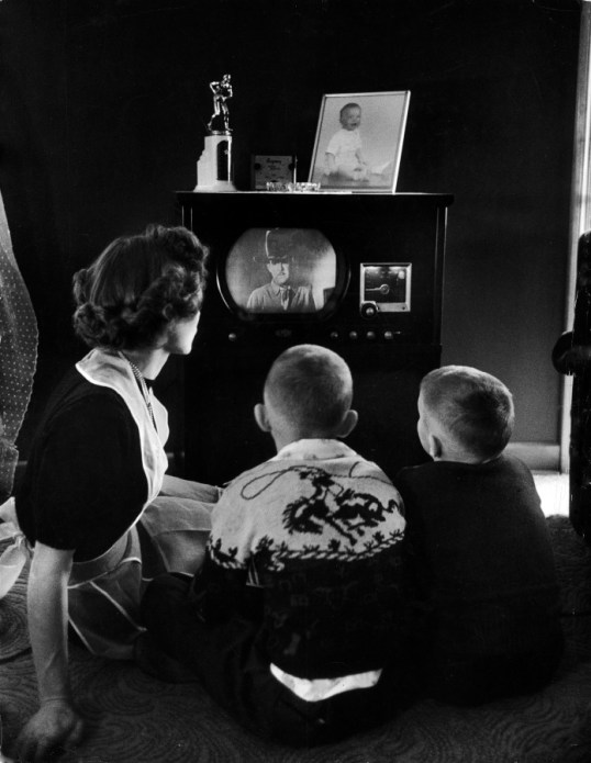 Mother and two children sitting on floor of living room